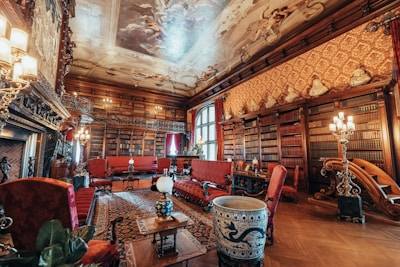 An elegant, classical study room bathed in golden light, lined with books and art pieces.