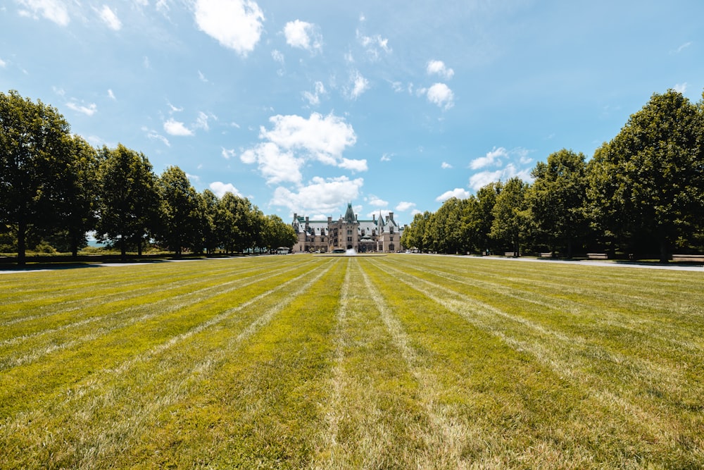 a large grassy field with a large building in the background