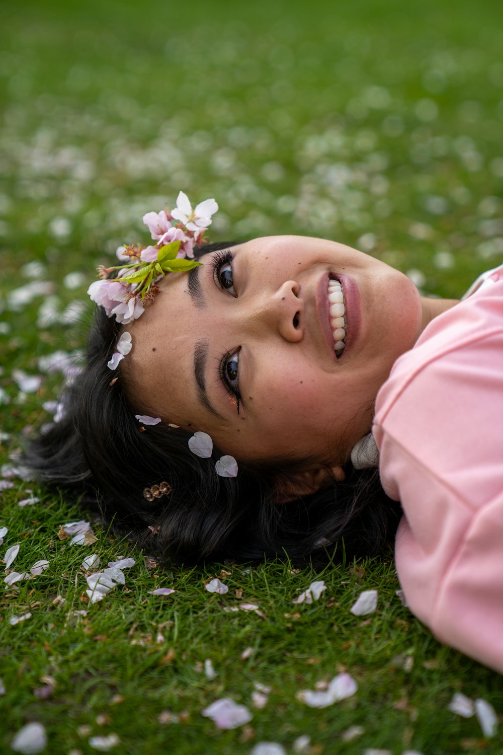 a woman laying on the grass with a flower in her hair