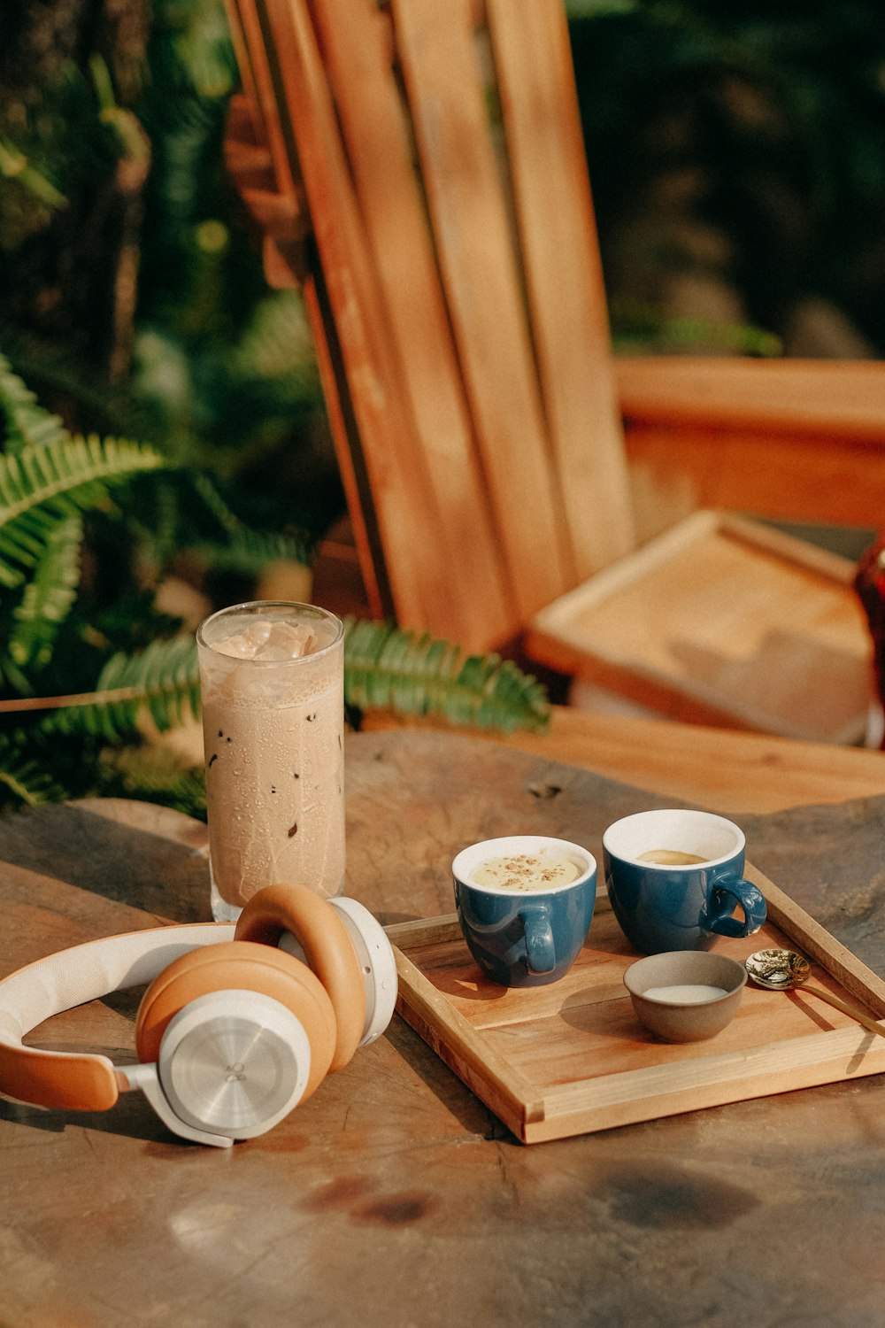 a wooden table topped with two cups of coffee and headphones