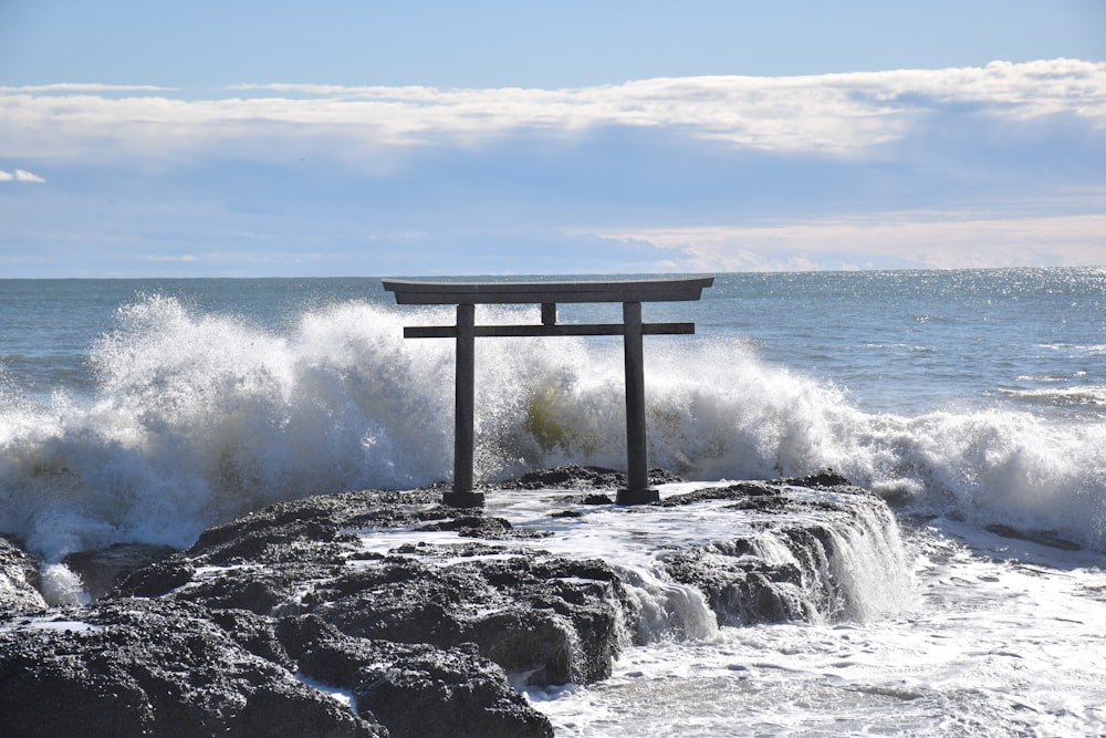 a wooden bench sitting on top of a rock next to the ocean