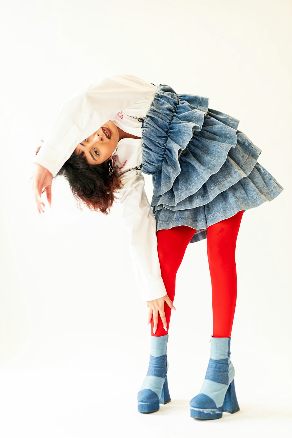 a woman in a skirt and boots is posing for a picture