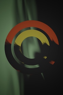 The image contains three concentric circles with varying colors suspended against a background that appears to blend dark green and black hues. The outer circle is orange, the middle circle is a dark greenish-black, and the inner circle is yellow. The background features a gradient effect with vertical, wave-like patterns in green and black.