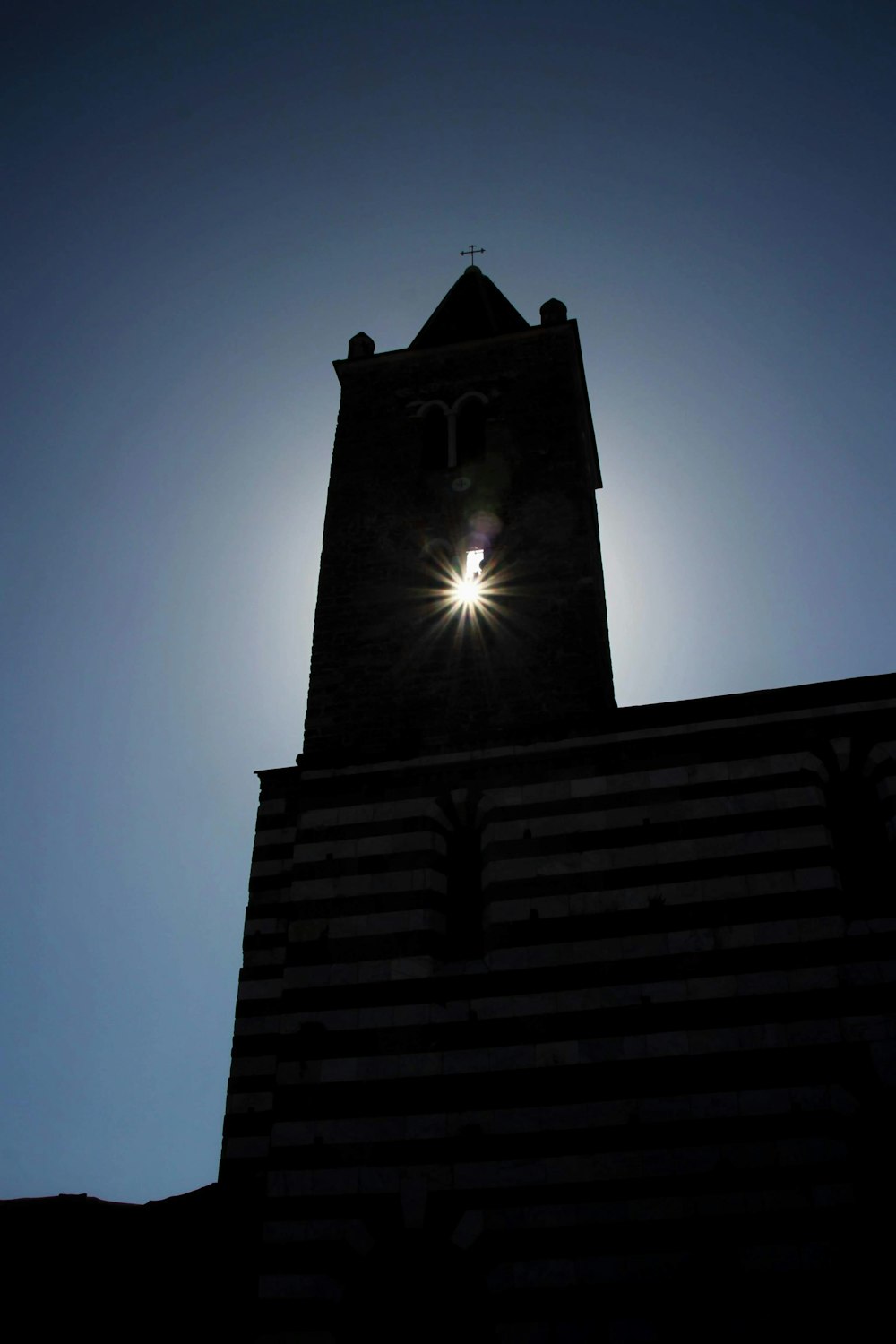 a clock tower with the sun shining behind it