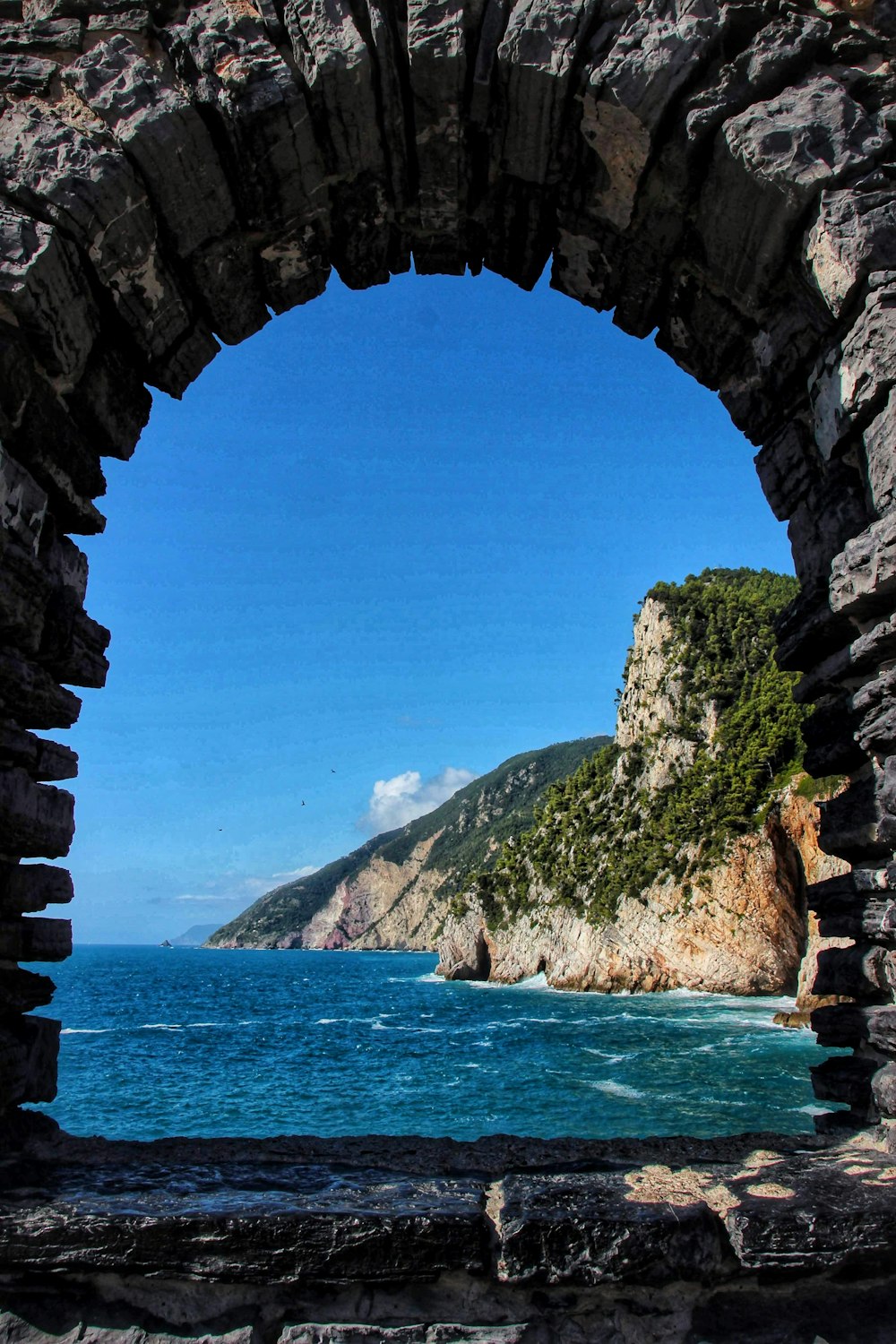 a view of a body of water through a stone arch