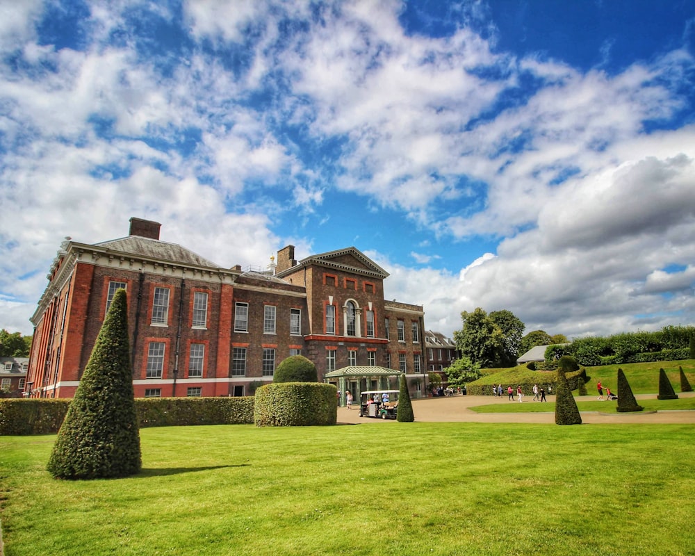 a large red brick building sitting on top of a lush green field