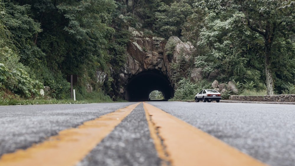 a car driving through a tunnel in the middle of a road