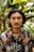 a man with a moustache standing in front of some plants