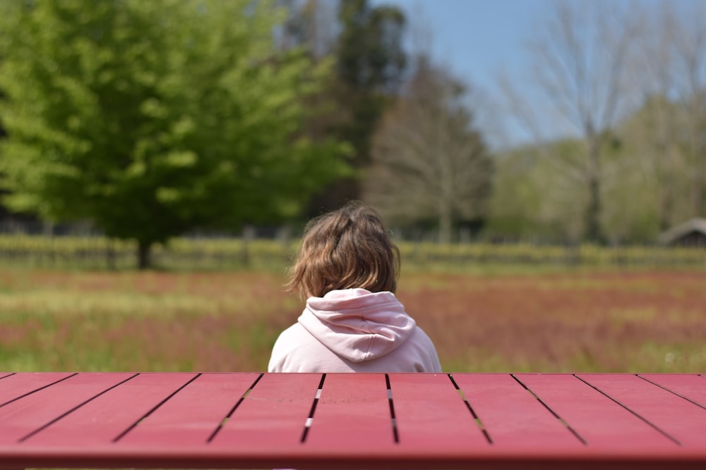 a little girl sitting at a red picnic table