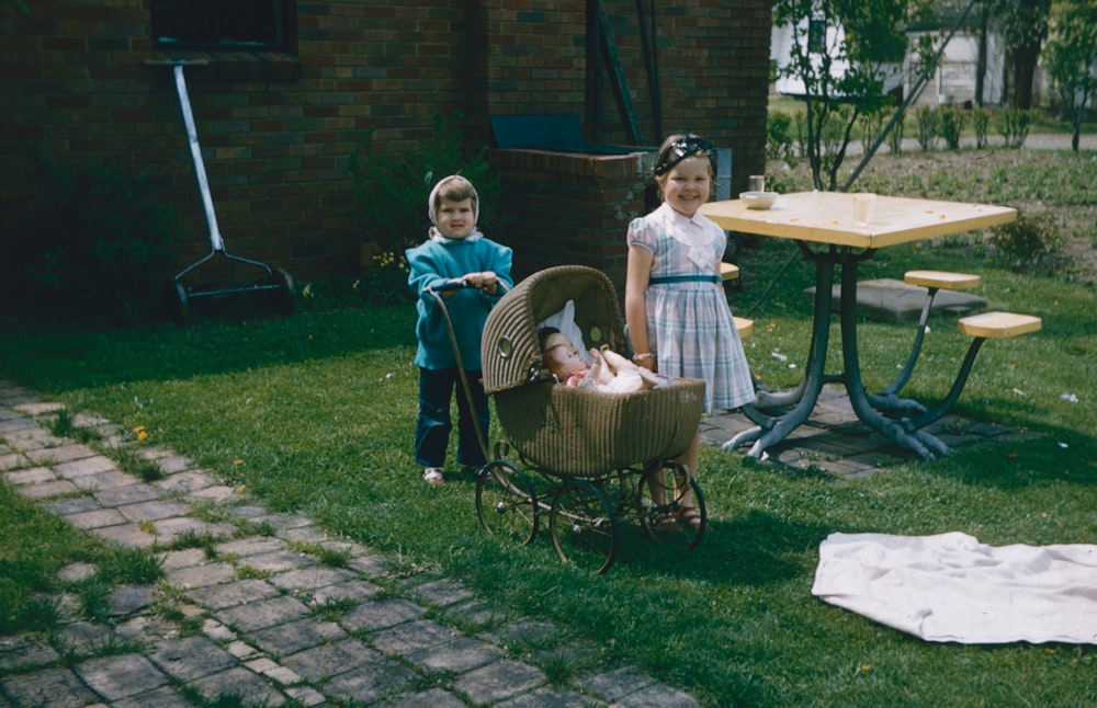 two little girls standing next to a baby carriage