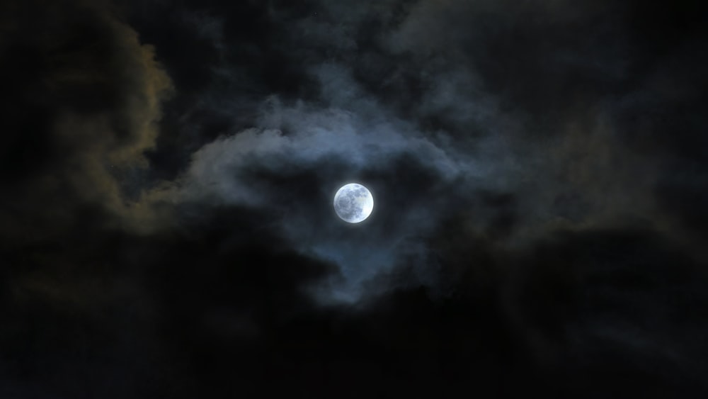 a full moon is seen through the clouds