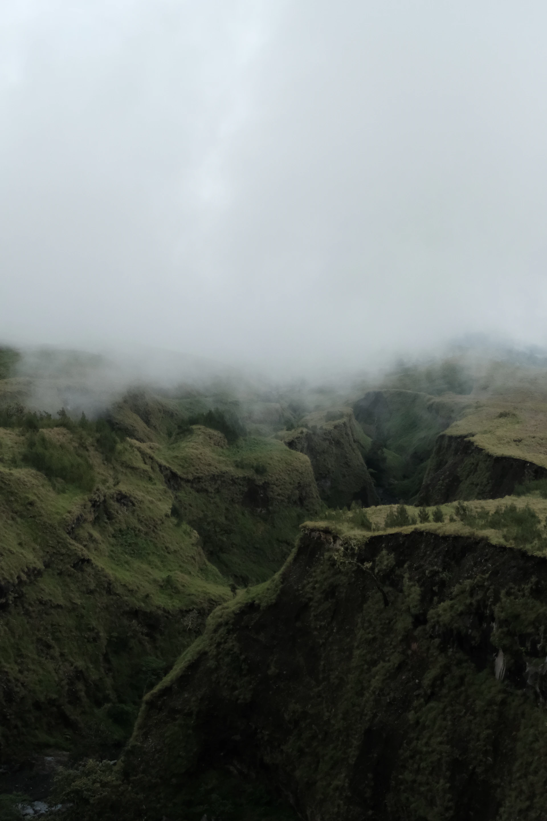 a foggy landscape with hills and a river