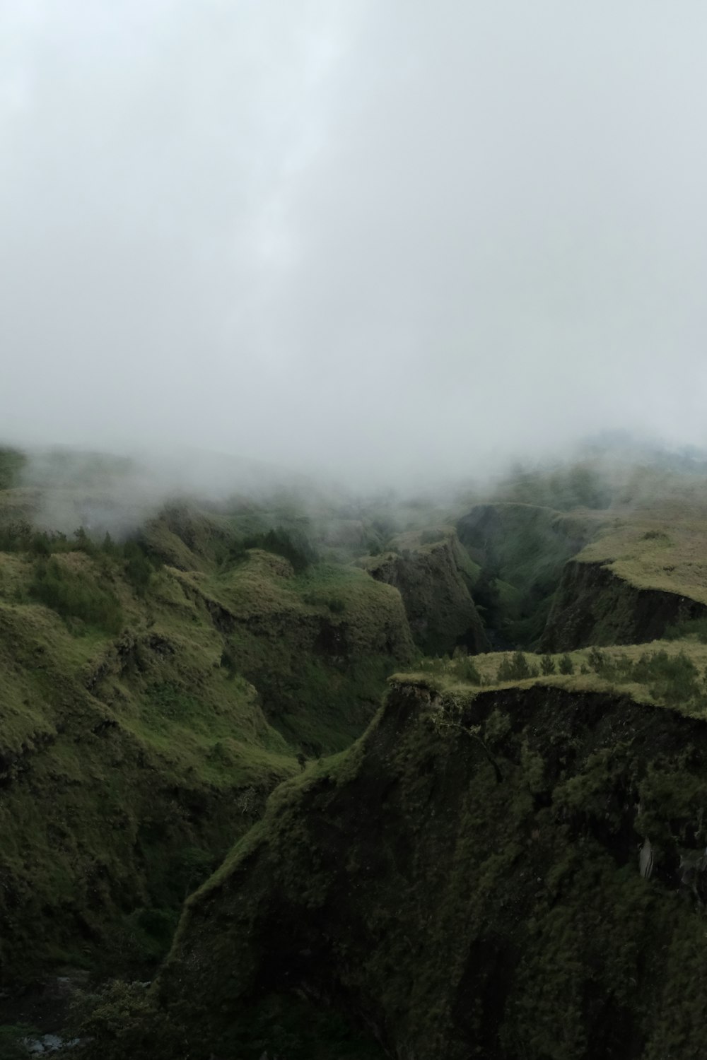 a foggy landscape with hills and a river