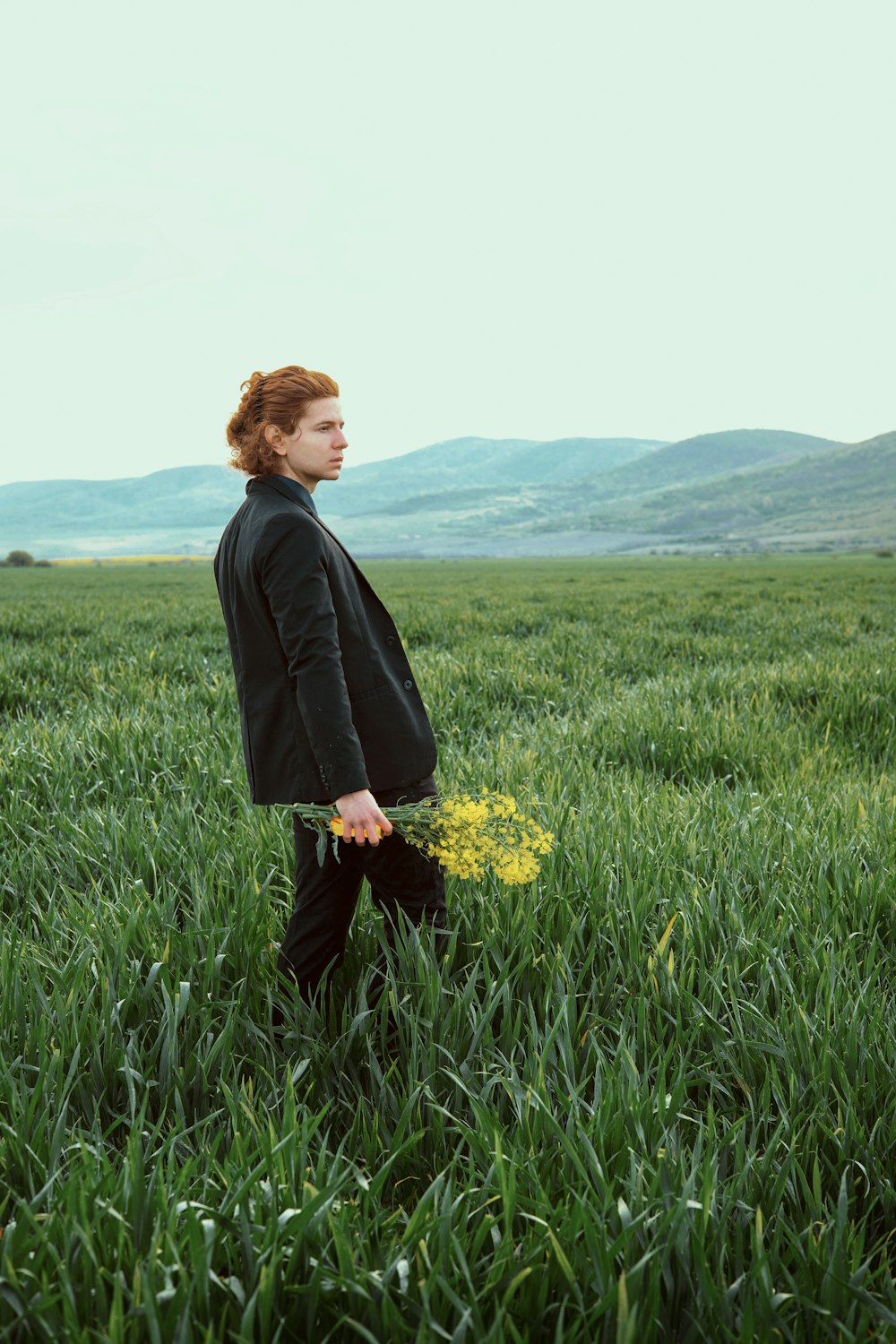 a woman standing in a field holding a yellow flower