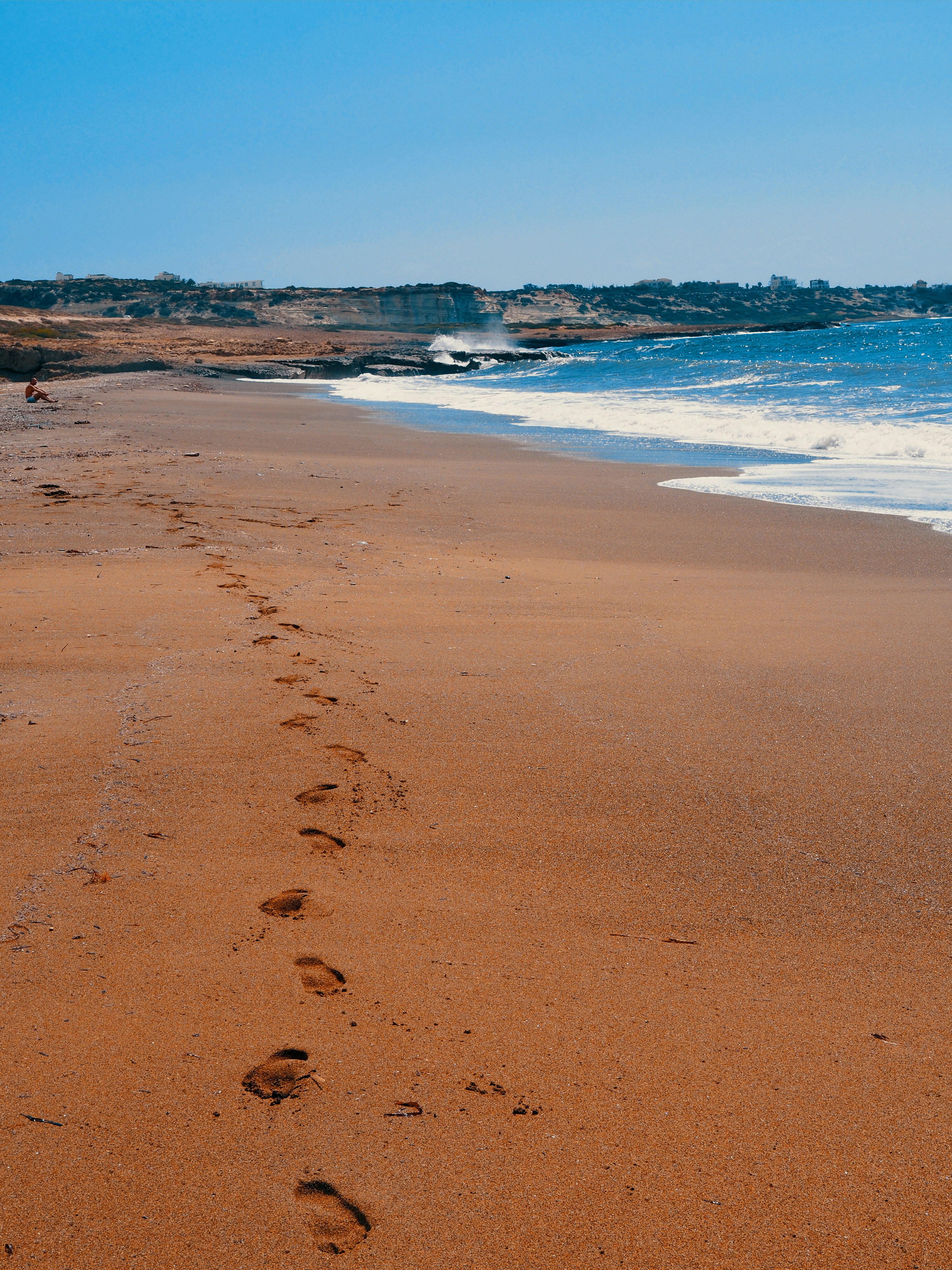 a person walking along a sandy beach next to the ocean
