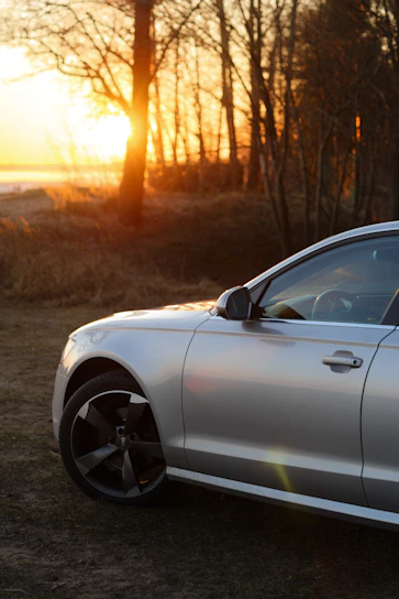 A sleek silver SUV parked by a scenic airport terminal at sunset.