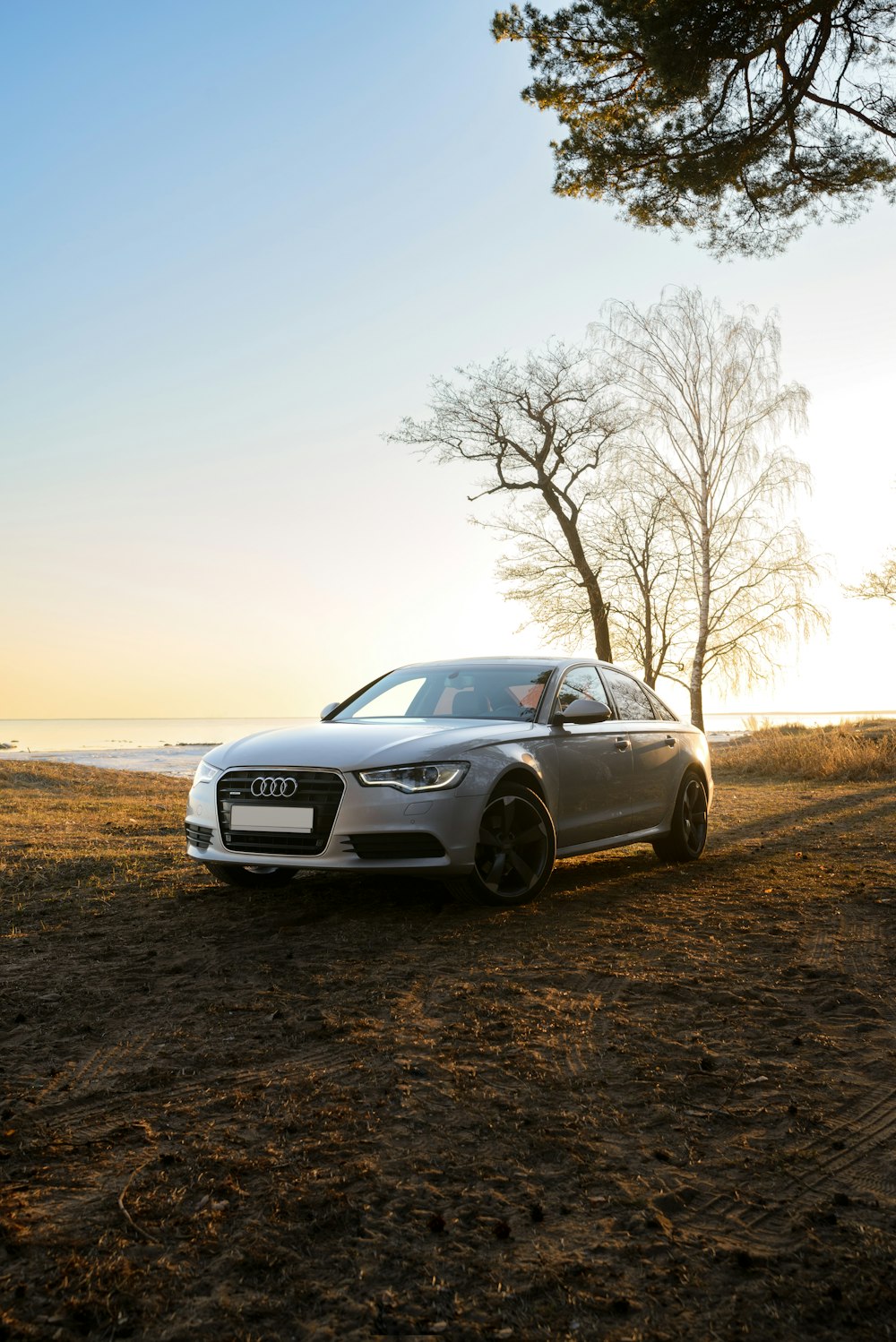 a silver car parked on the side of a dirt road