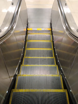 an escalator in a subway station with yellow lines