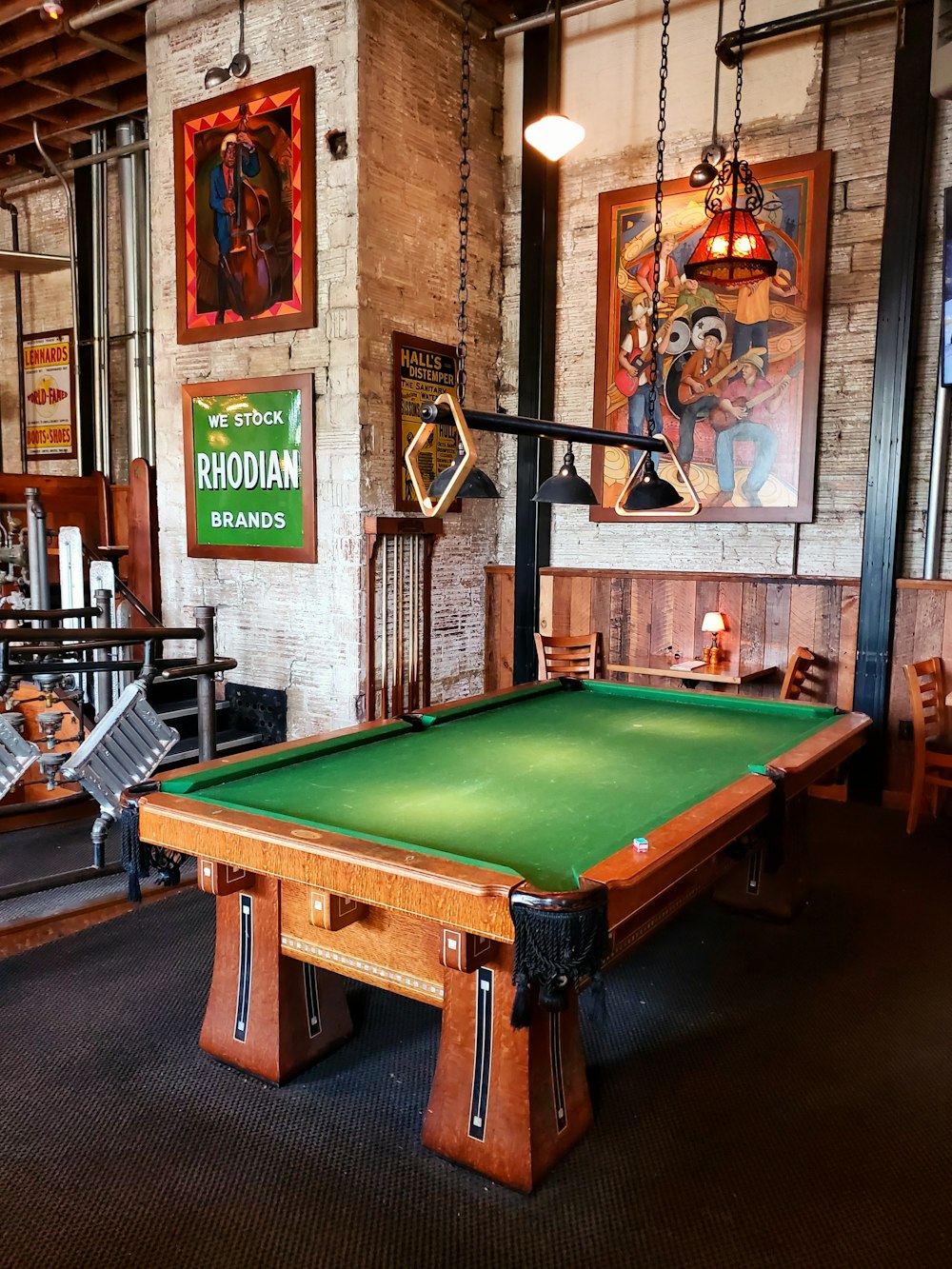 a green pool table in a room with pictures on the wall