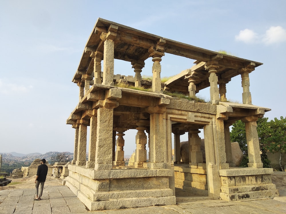 a man standing in front of a stone structure