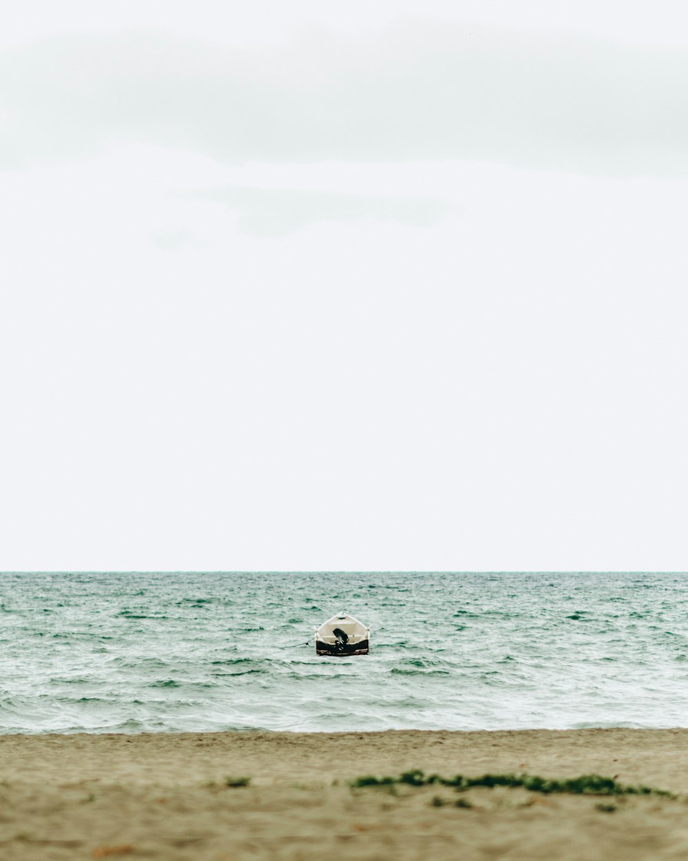 a lone boat floating in the middle of the ocean