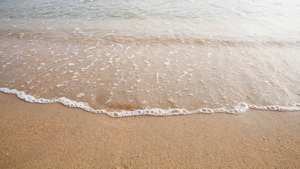 a sandy beach with waves coming in to shore