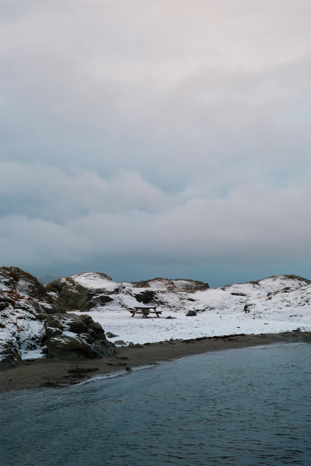 a body of water surrounded by snow covered hills