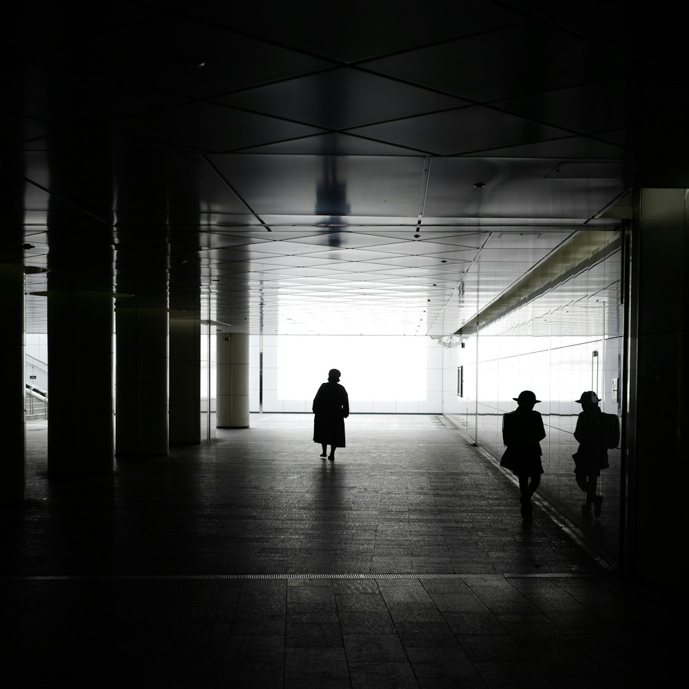 two people are walking down a dark hallway