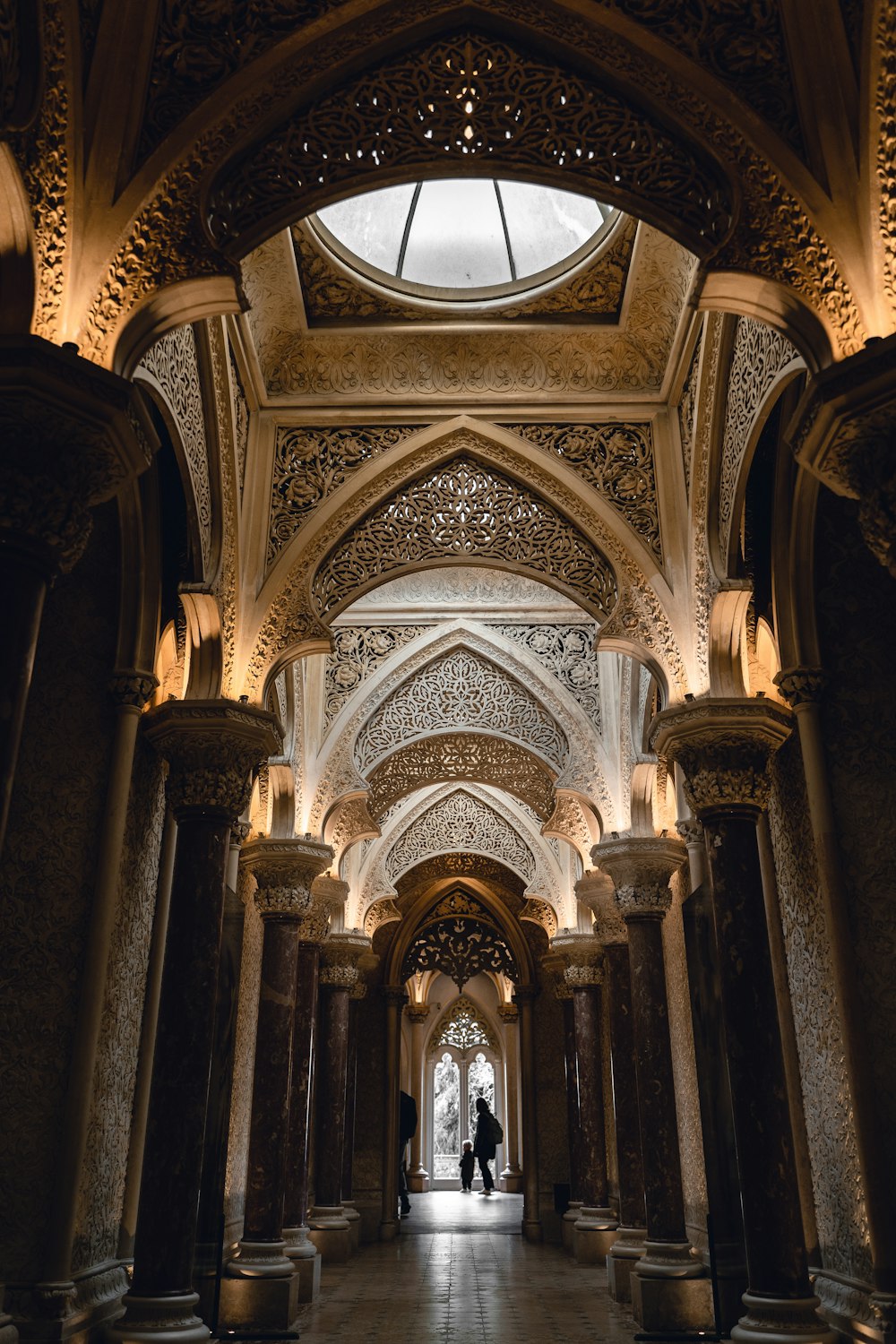 a long hallway with columns and a clock on the ceiling