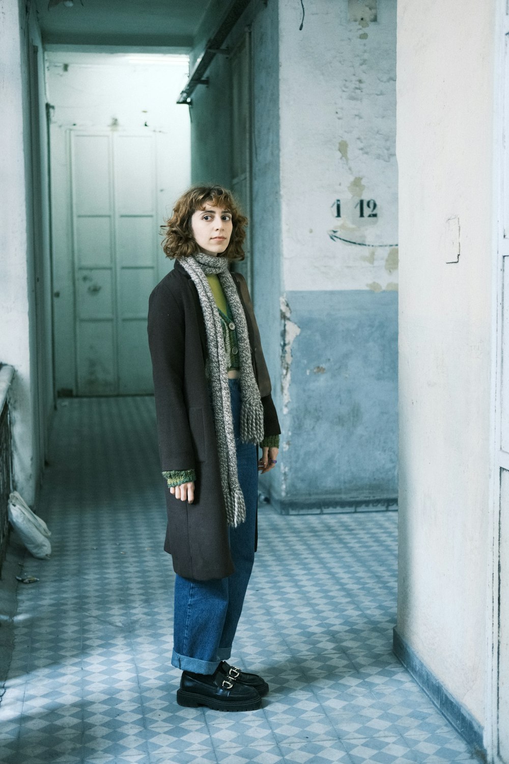 a woman standing in a hallway with a scarf around her neck