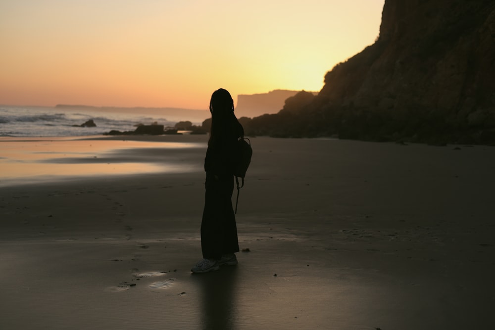 a person standing on a beach at sunset