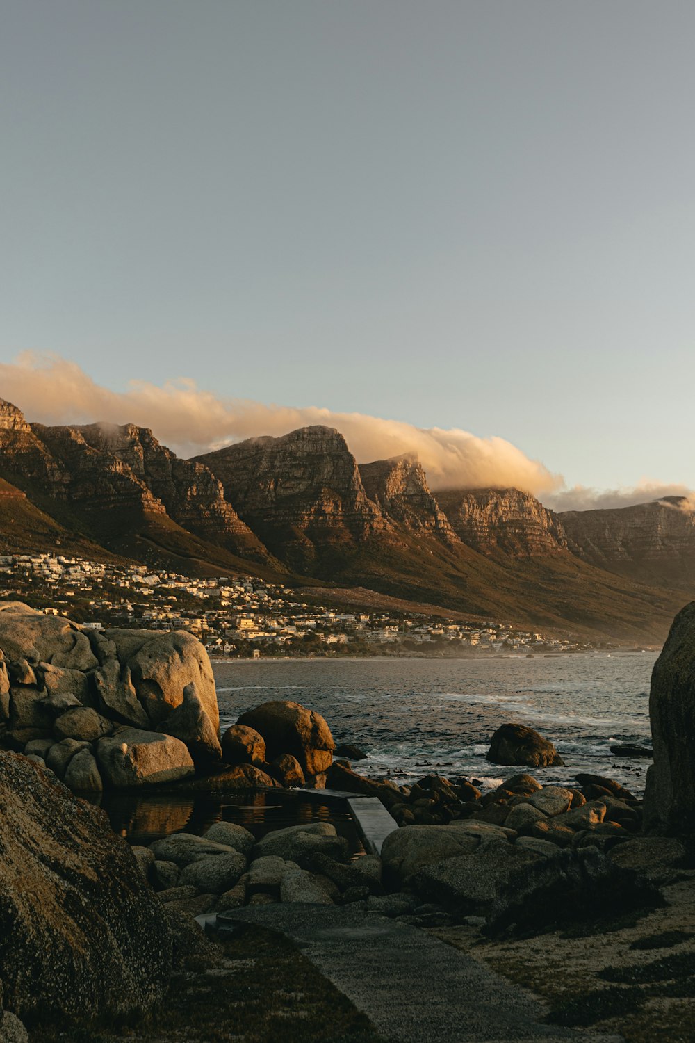 a rocky shore with a body of water and mountains in the background