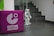 A small humanoid robot stands at the base of a staircase with tiled steps. To the left, a purple cube with the logo and words 'Goethe Institut' is visible. The floor is also tiled, and the surrounding walls are mostly plain.