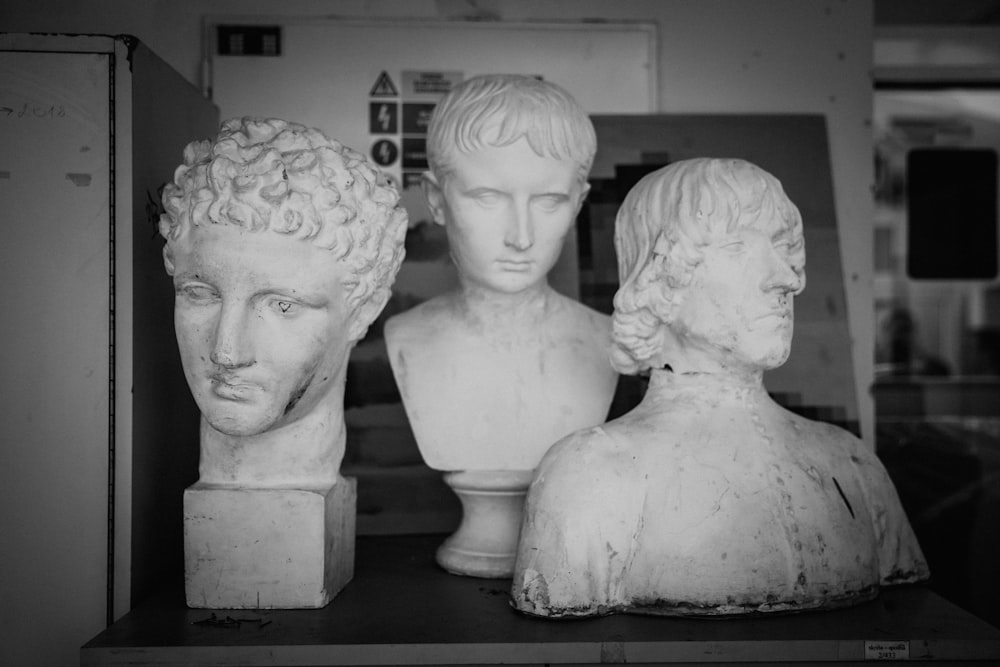a black and white photo of three busts of men