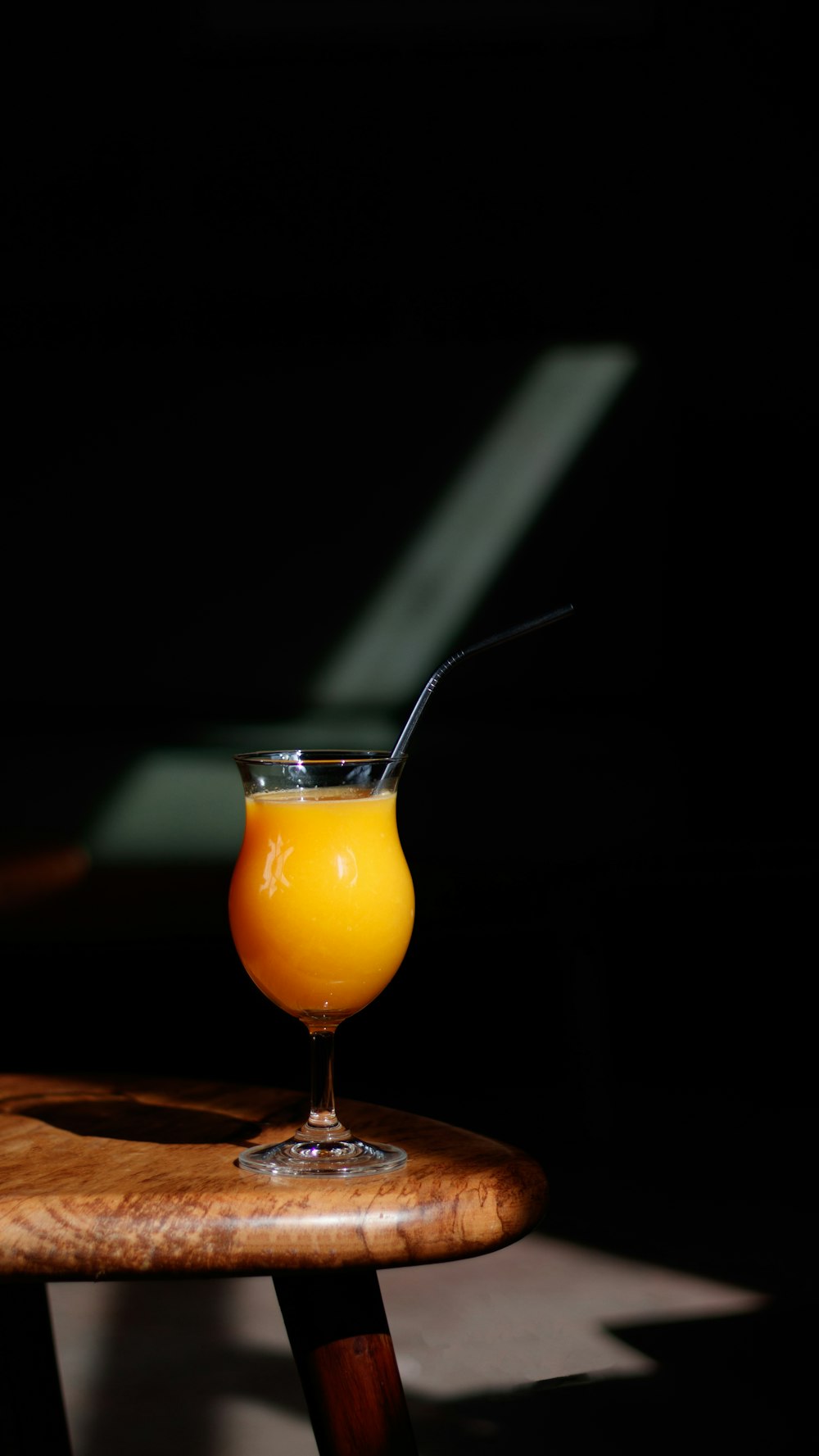 a glass of orange juice sitting on top of a wooden table