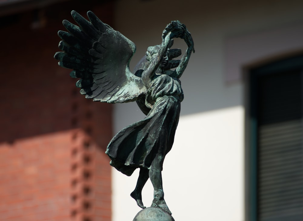 a statue of a woman holding a bird on top of a pole