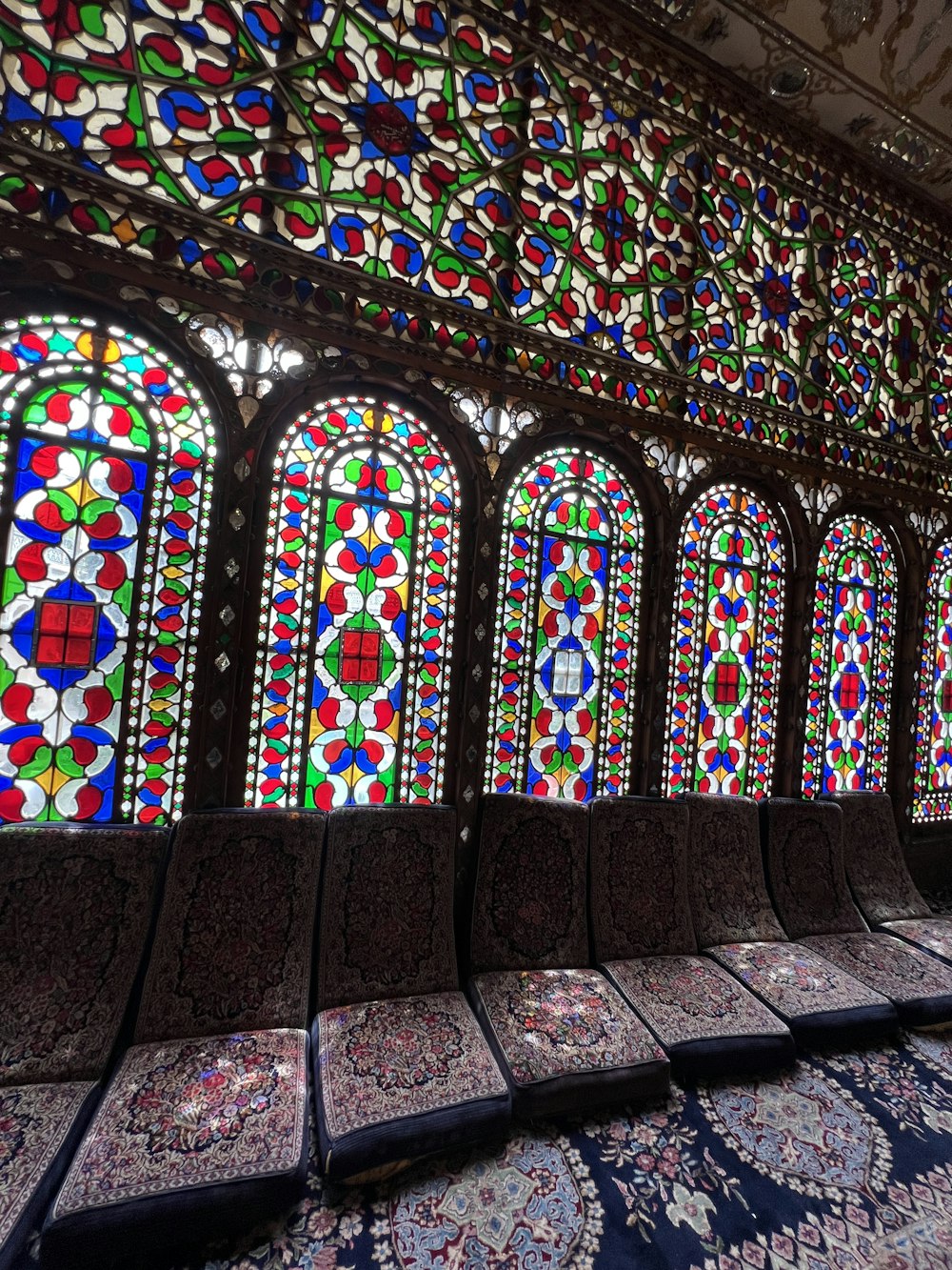 a row of benches in front of stained glass windows