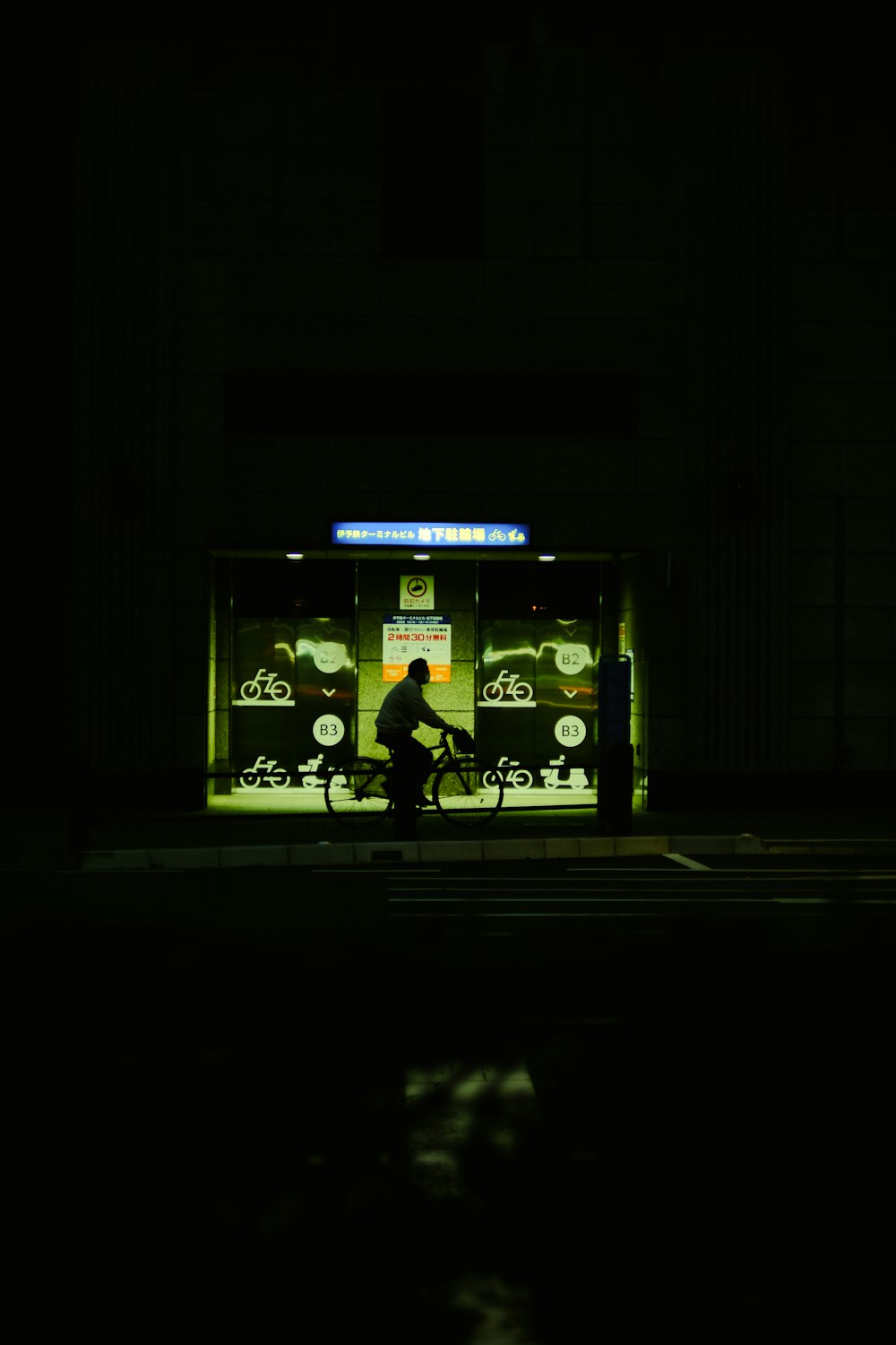 a man riding a bike at night in front of a bus stop