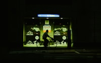a man riding a bike at night in front of a bus stop