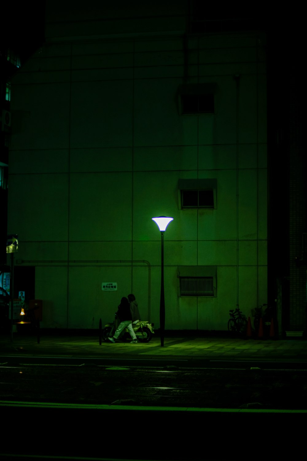 a person sitting on a bench under a street light