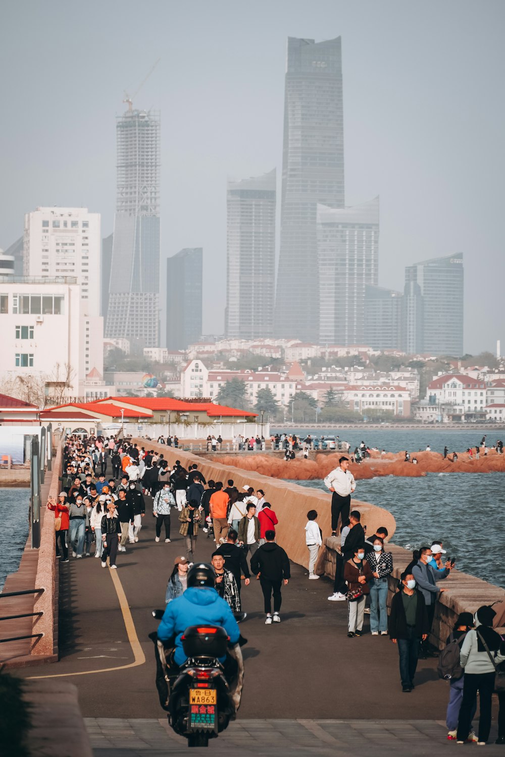 a group of people walking along a pier next to a body of water