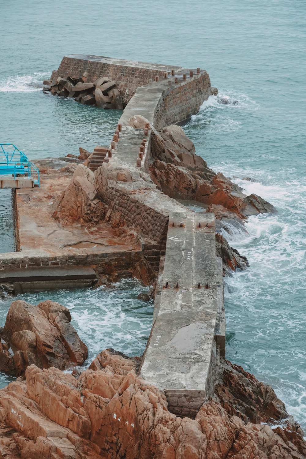 a blue bench sitting on top of a rocky shore