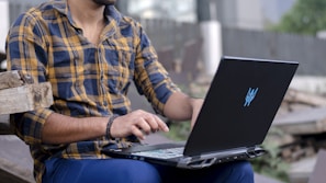 Person typing on a laptop outdoors with a blurred city background.