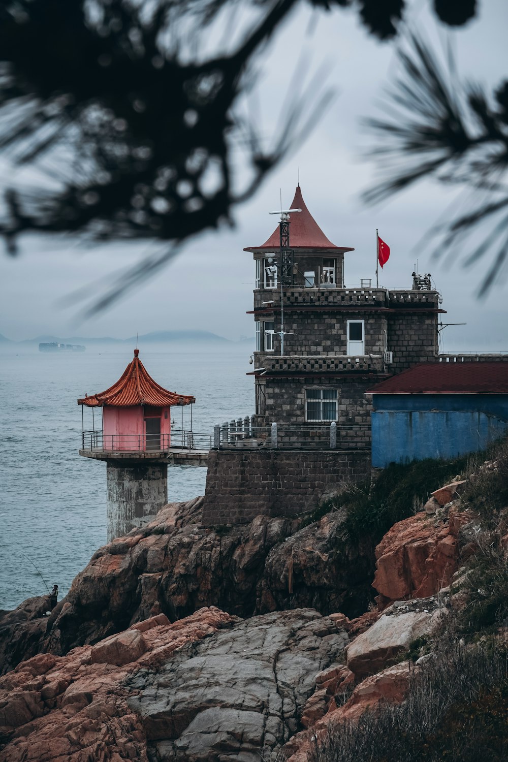 a red and white lighthouse sitting on top of a rocky cliff
