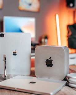 a couple of apple computers sitting on top of a wooden table