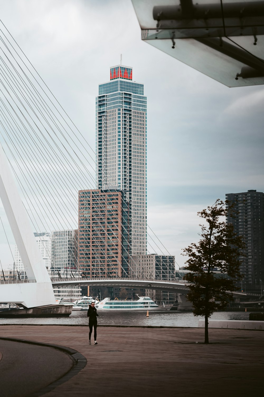 Eine Person, die vor einer Brücke mit einem hohen Gebäude im Hintergrund steht