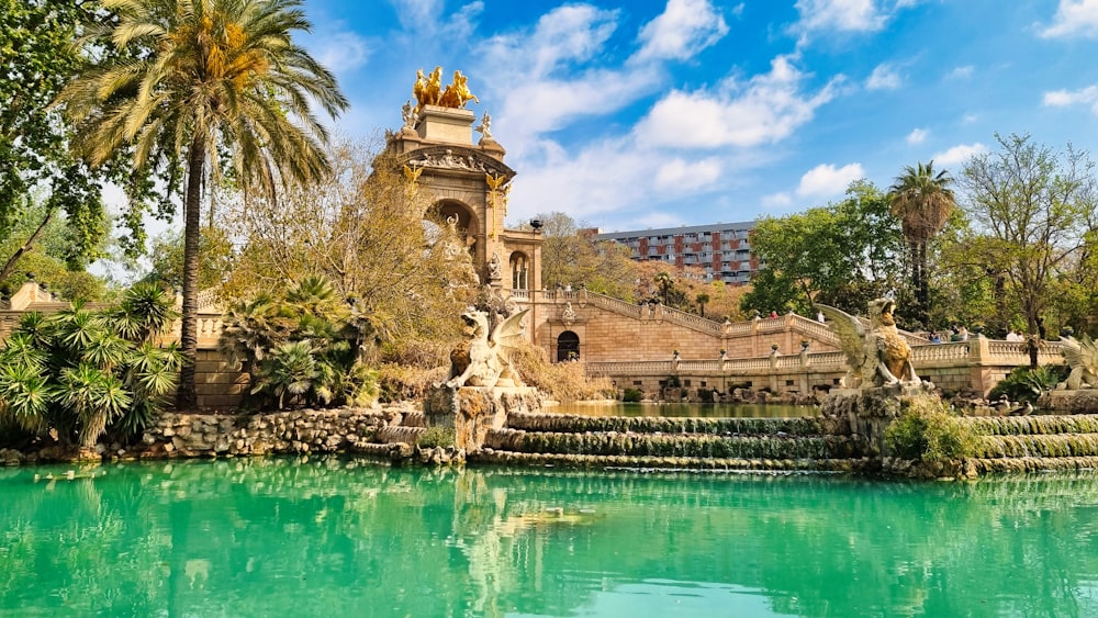 a pond with a fountain surrounded by palm trees