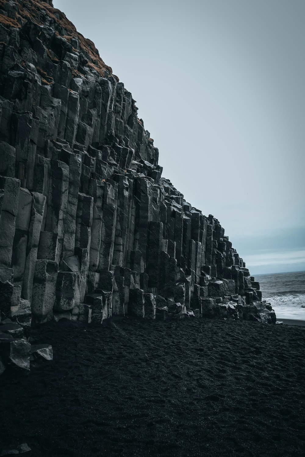 a large rock formation on a beach next to the ocean