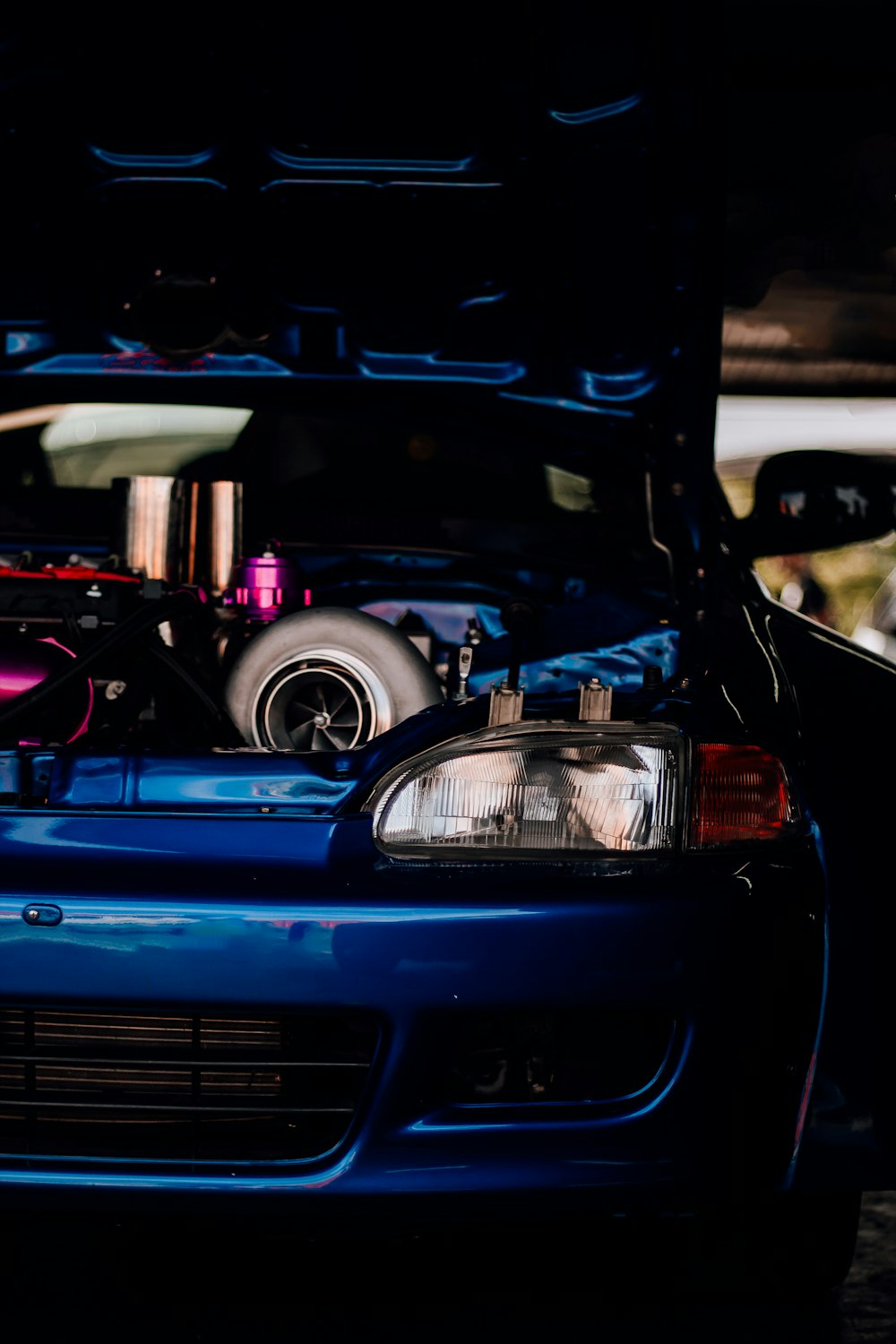 a blue car with its hood open in a garage