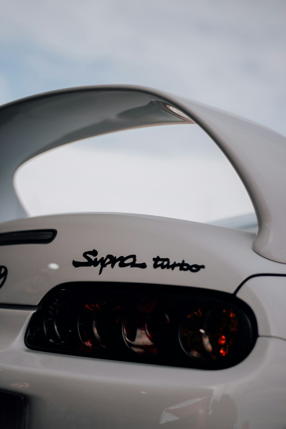 a close up of a white sports car with a sky background